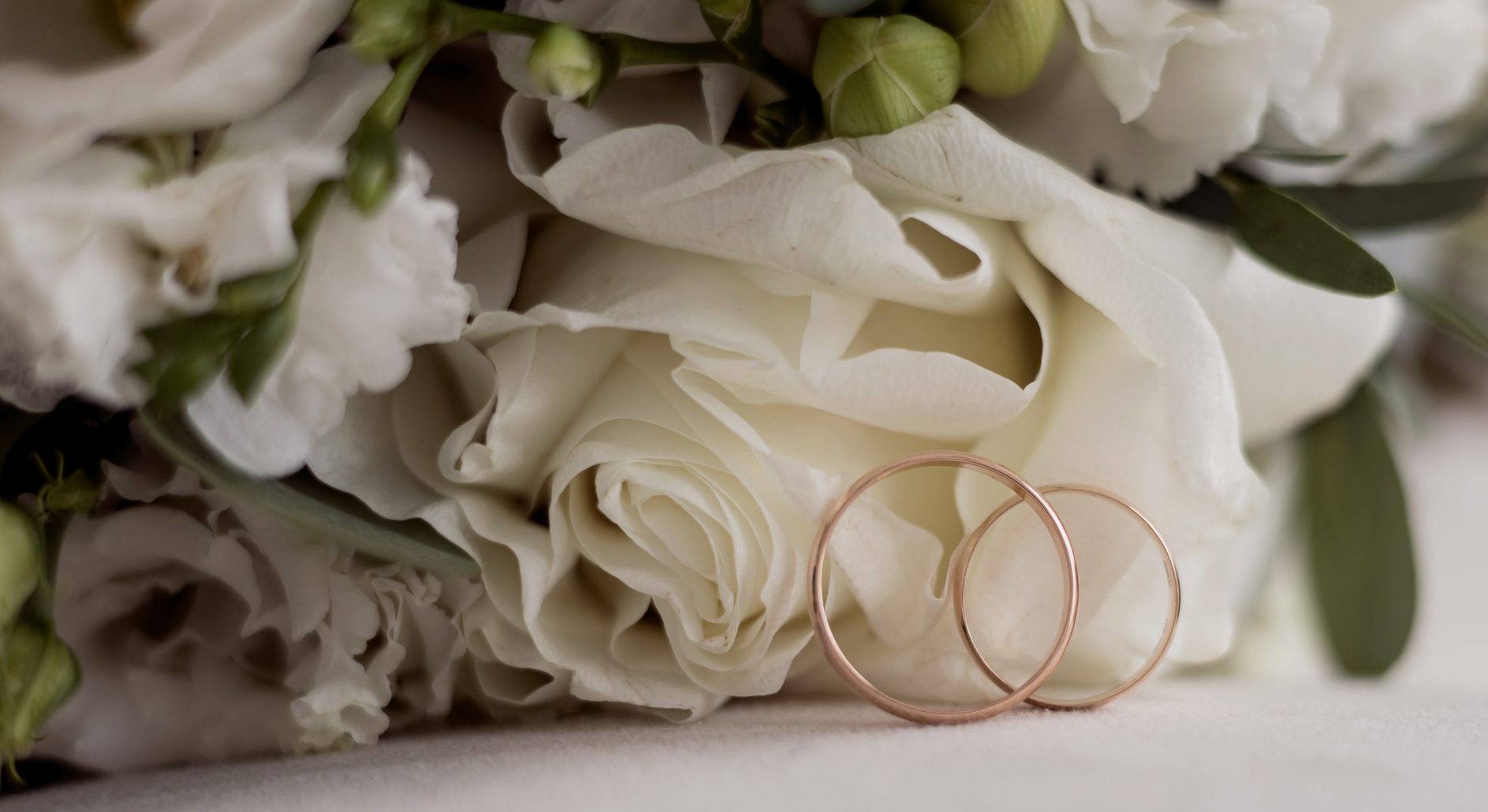 Elegant wedding rings near beautiful bouquet of flowers
